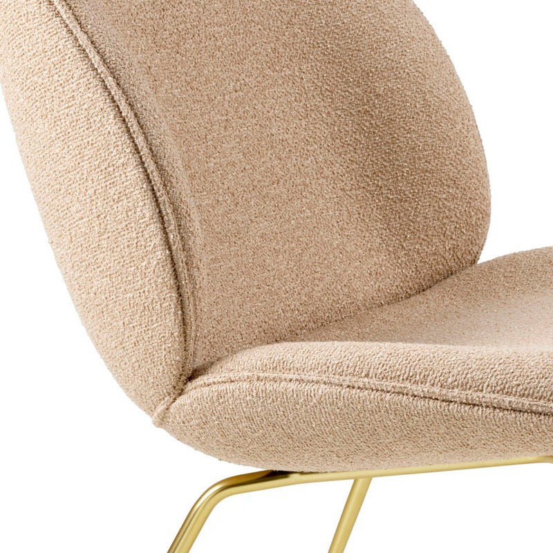 Close-up of beige boucle fabric chair seat and backrest with curved edges and polished gold metal legs