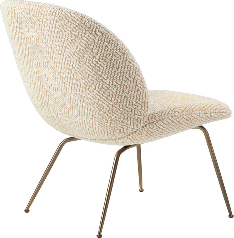 Curved lounge chair with cream geometric patterned fabric and thin angled bronze metal legs