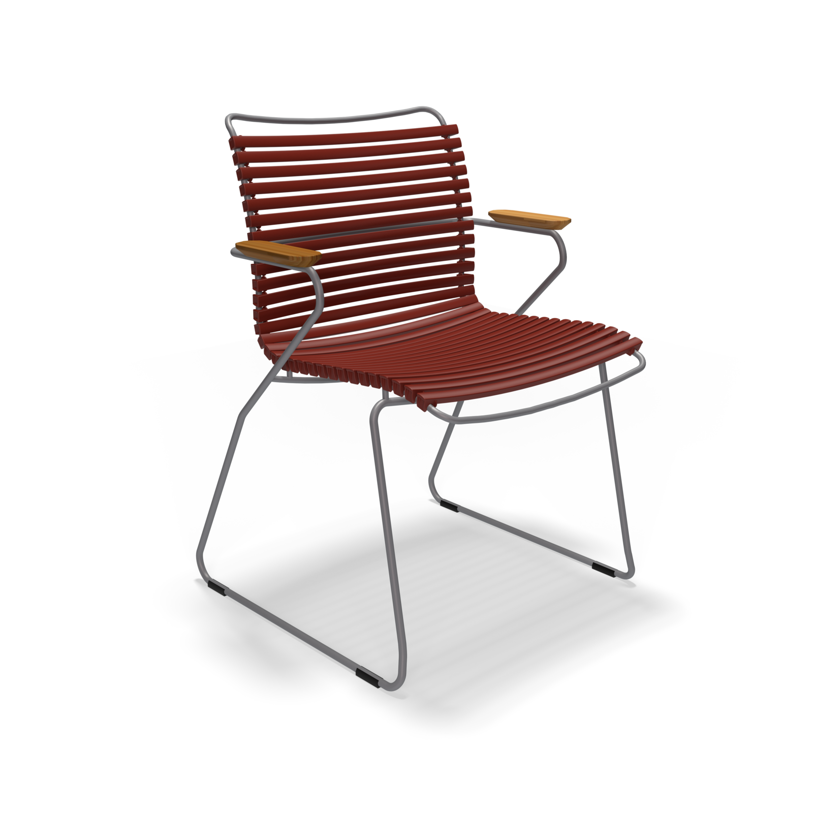 The Click Dining Chair with Armrest by Houe is a modern outdoor chair featuring a sleek black metal sled base, weather-resistant red slatted seat and backrest, light wooden armrests, and durable plastic lamellas.