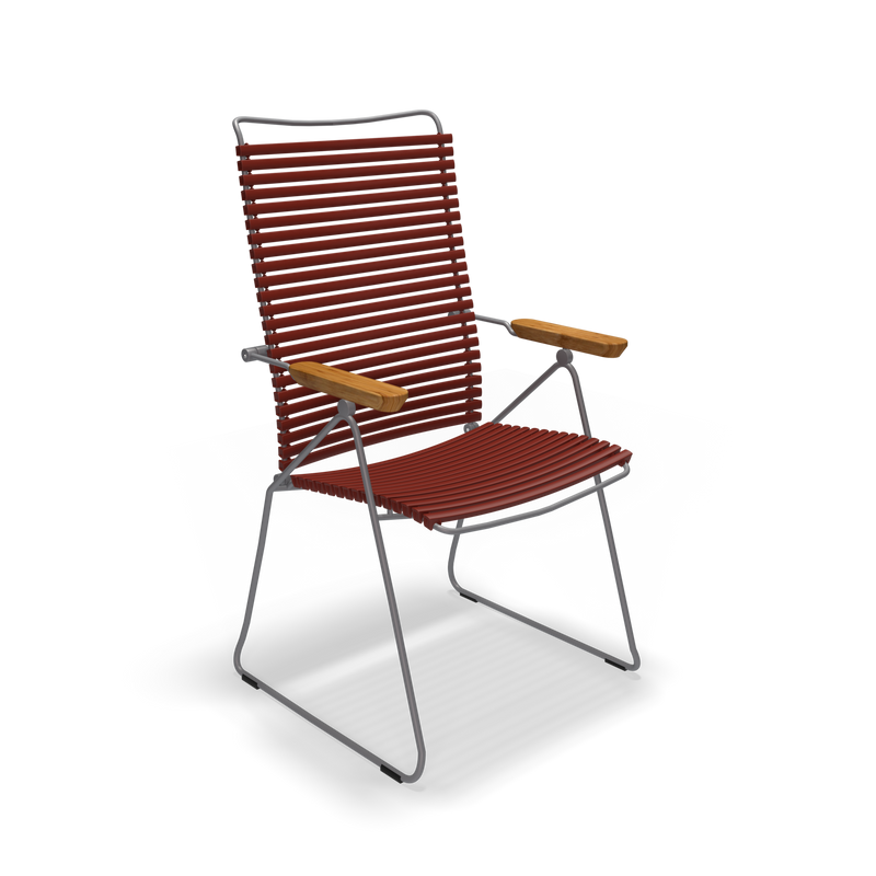 The Click Position Chair by Houe is a modern outdoor chair with a weather-resistant dark metal frame and durable plastic lamellas in horizontal red slats for the seat and backrest. It features wooden armrests, showcasing a minimalist design set against a plain black background.