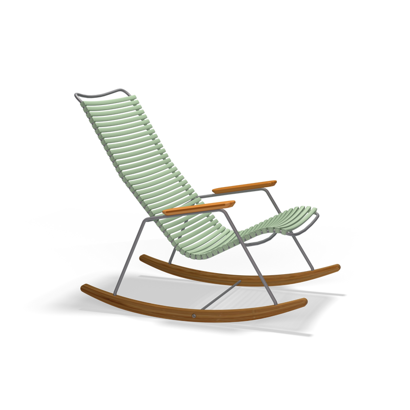 The Click Rocking Chair by Houe is a modern outdoor chair featuring light green ribbed cushions on a slim metal frame with wooden armrests and rocker legs, all set against a solid black background.