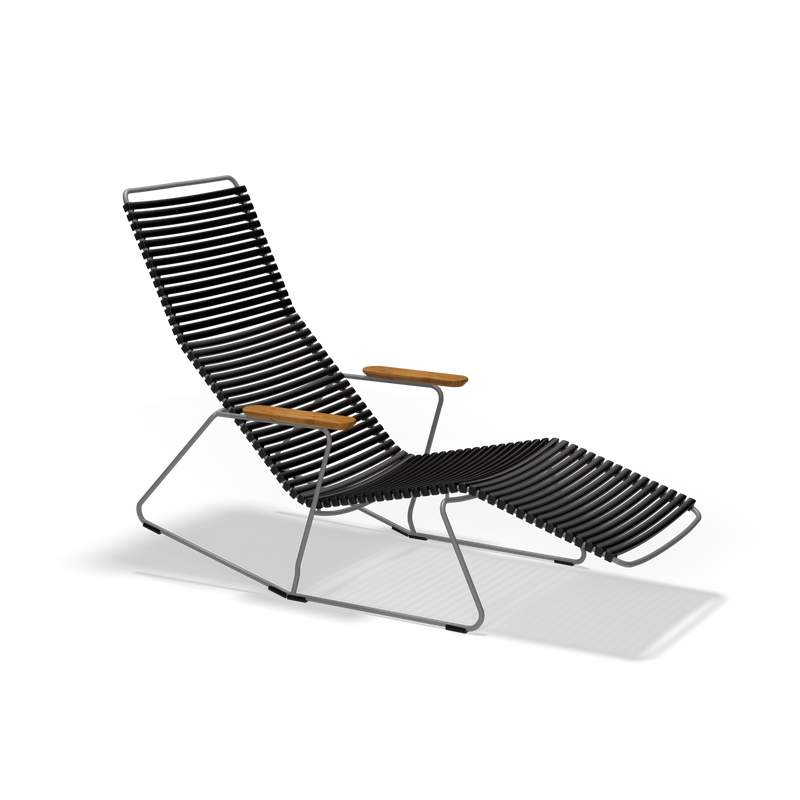 The Click Sunrocker by Houe is a sleek black lounge chair with a ribbed design and wooden armrests, featuring an inclined backrest and footrest. It combines metal with stylish bamboo elements for an elegant touch, beautifully set against a black background.