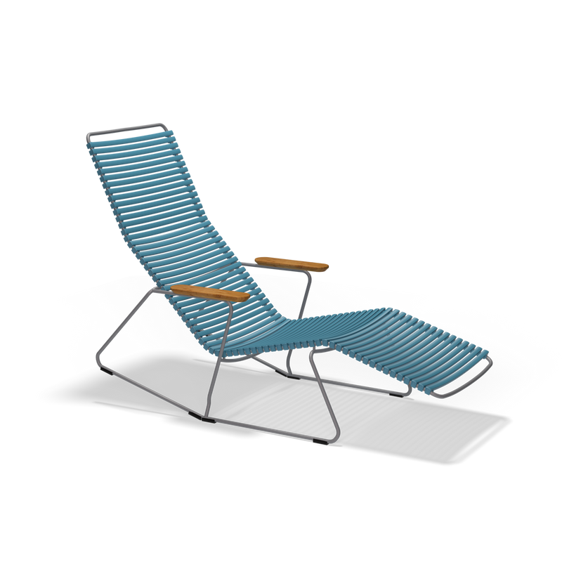 The Click Sunrocker by Houe is a modern lounge chair with a minimalist design, featuring a powder-coated steel frame and blue slatted seat. It includes armrests with wooden accents and an extended leg rest, making it stylish for outdoor relaxation.