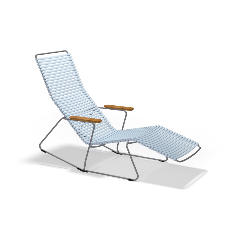 The Click Sunrocker by Houe is a stylish lounge chair with a sleek, curved powder-coated steel frame and light blue slatted design. It includes wooden armrests and an extended footrest, offering comfortable seating against a plain black background.