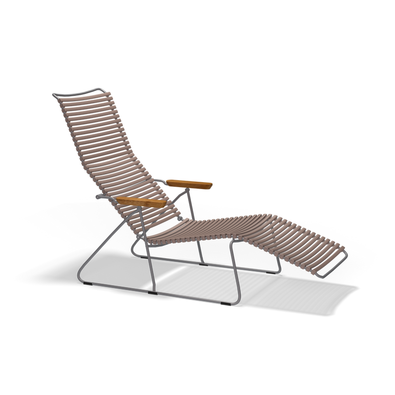 The Click Sunlounger by Houe features a minimalist tubular metal frame with brown woven rope for the seat and backrest, wooden armrests, and a leg extension. Perfect for outdoor seating, this modern chair stands stylishly against a sleek black background.