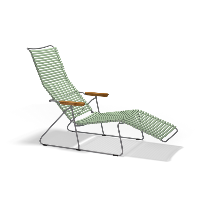The Click Sunlounger by Houe is a modern, minimalist outdoor lounge chair with a metal frame and light green corded seat. It features UV-protected, cushion-free seating, wooden armrests, and a reclining footrest against a black backdrop.