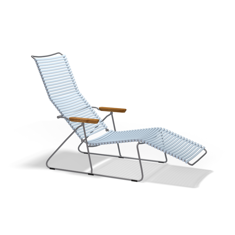 The Click Sunlounger by Houe is a modern outdoor lounge chair with a sleek, UV-protected design. It features a long white slatted body, wooden armrests, and a metal frame. This cushion-free seating offers an elongated seat and backrest against a striking black background.
