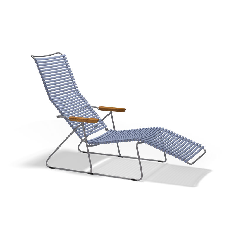 The Click Sunlounger by Houe is a modern lounge chair featuring a sleek, silver metal frame with a blue woven seat and backrest. It has wooden armrests and offers reclining for relaxation. Ideal for outdoor use, its UV protected and strikingly stands out against a black background.