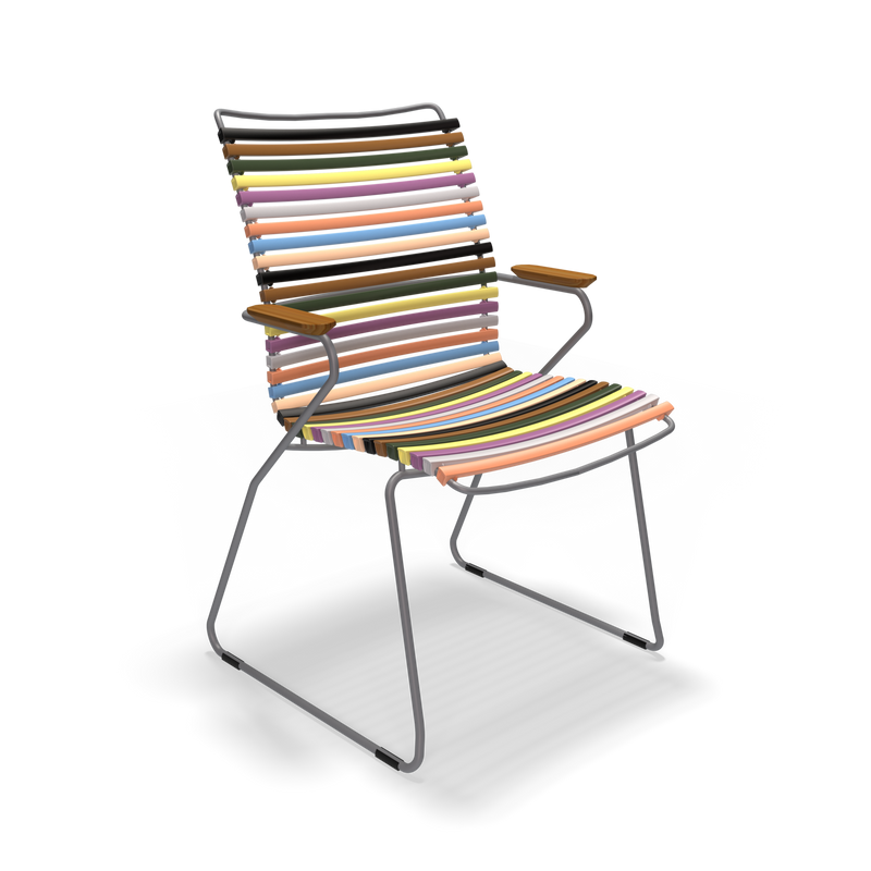 The Click Dining Chair with Armrest - Tall Back by Houe features a metal frame and horizontal, UV-protected, multi-colored slats. It includes wooden armrests and offers a colorful, weather-resistant modern design against a black background, perfect for outdoor use.