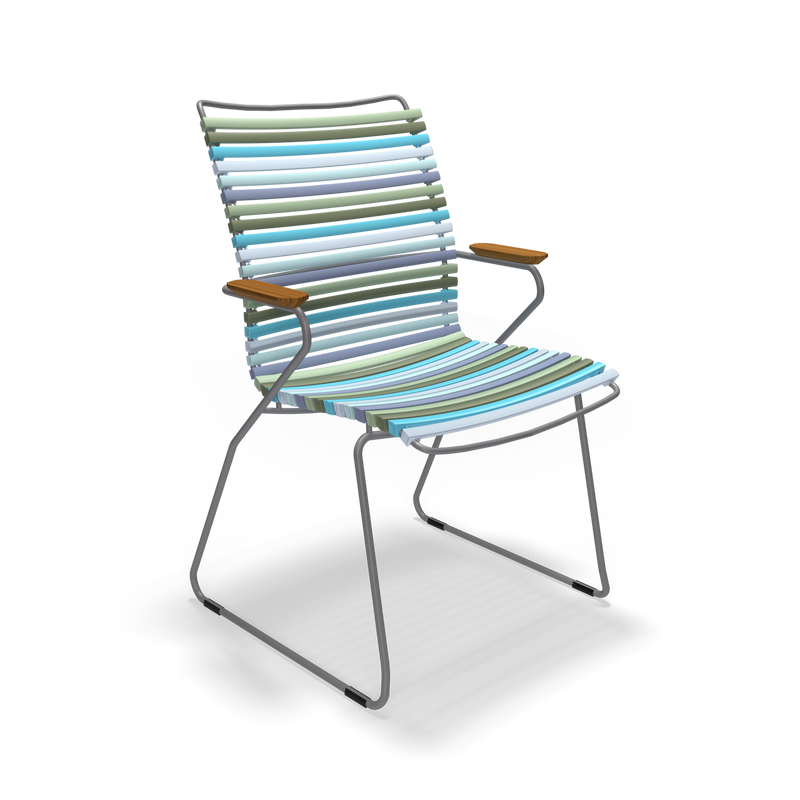 The Houe Click Dining Chair with Armrest - Tall Back is a modern outdoor chair featuring a striped seat and back in blue, green, and white. It offers UV protection, weather-resistant materials, metal legs, wooden armrests, and a plain black background.