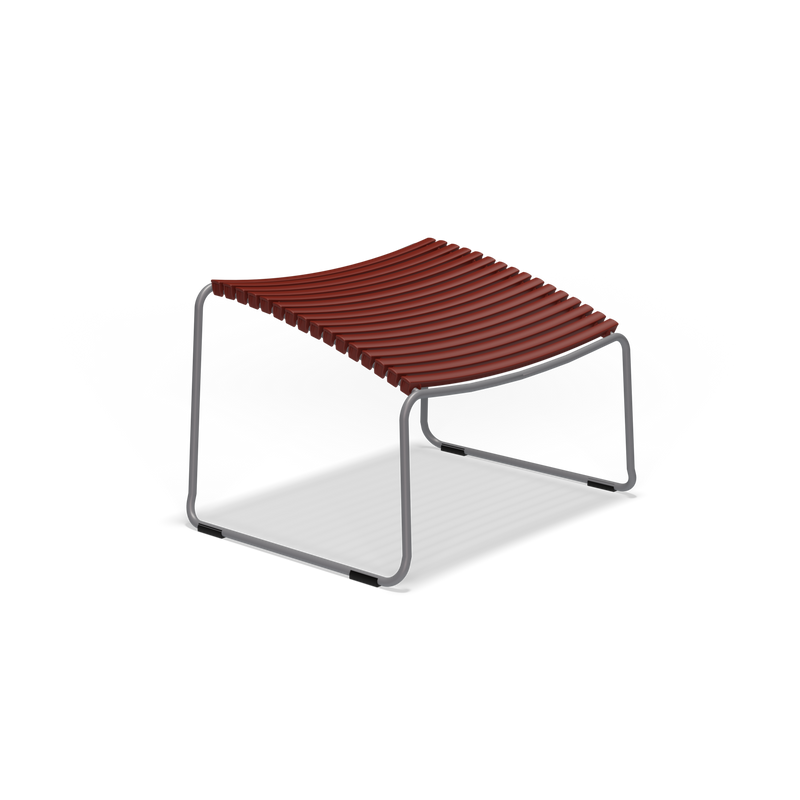 The Click Footrest by Houe is a modern footstool with a red slatted seat and sturdy metal frame. Its curved edges and minimalist style make it perfect for contemporary interiors, while its UV-protected design enhances durability for both outdoor chairs and any indoor space.