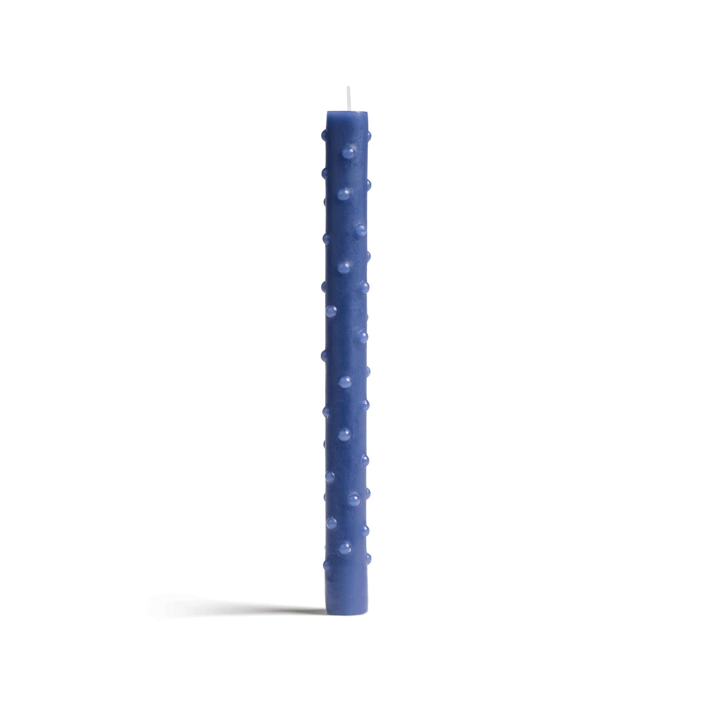 A tall, slender blue candle with a textured dotted surface stands against a white background. Made by &Klevering, this elegant piece features a visible wick at the top.