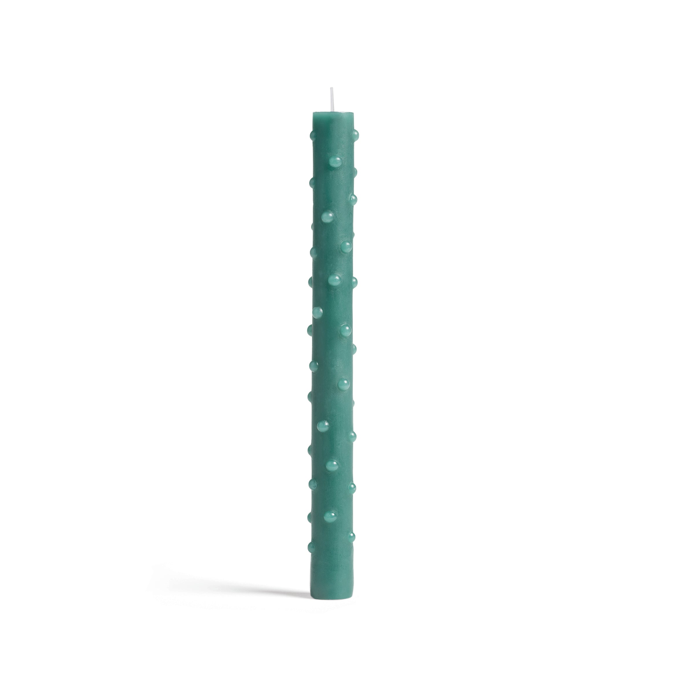 A tall, green candle from &Klevering showcases a textured surface with round protrusions. Unlit, it stands against a plain white background, embodying minimalist elegance.
