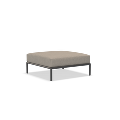 The Houe Level Ottoman features a minimalist design with a beige cushion and a sleek, powder-coated aluminum frame. Its simple lines integrate seamlessly with contemporary interiors.
