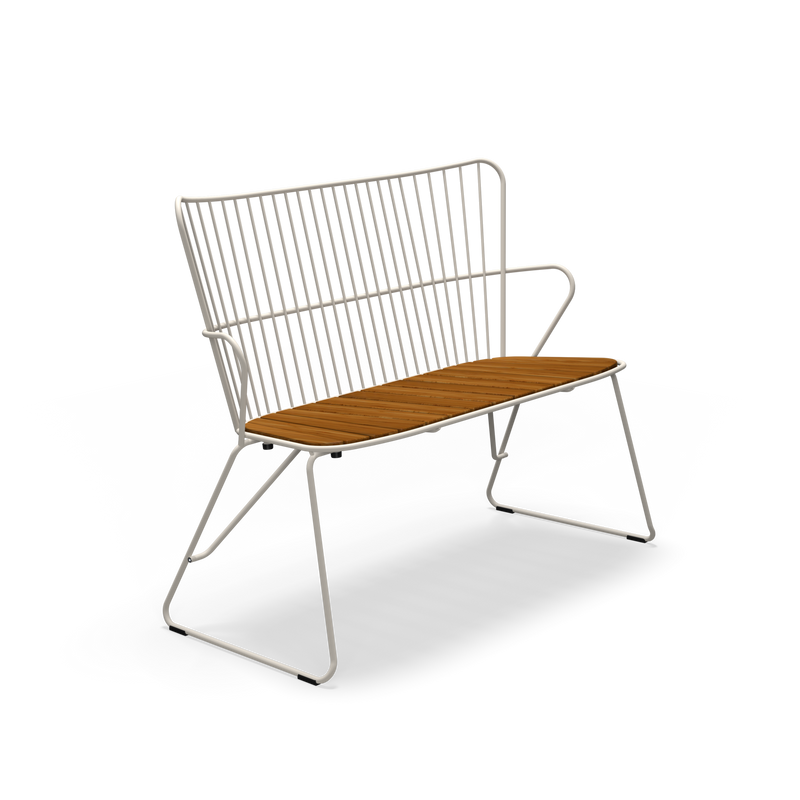 The Paon Bench by Houe features a modern Scandinavian design with a sleek white metal frame and wooden seat, complemented by a vertical slat backrest and angled metal legs, all highlighted against a black background.
