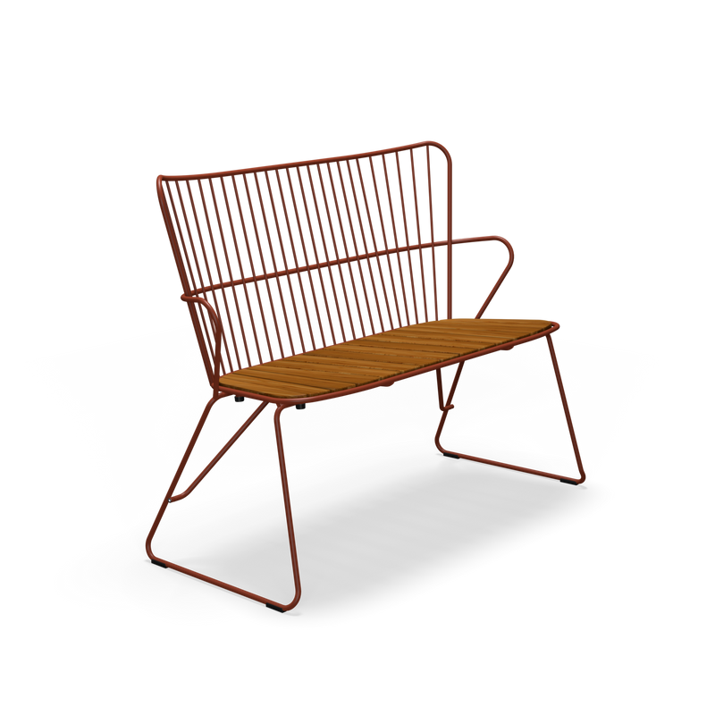 A modern Paon Bench with a rust-colored metal finish and minimalist Scandinavian design by Houe. It features a wire backrest, a wooden slatted seat, and sleek angled legs reminiscent of PAON chairs, all on a plain black background.