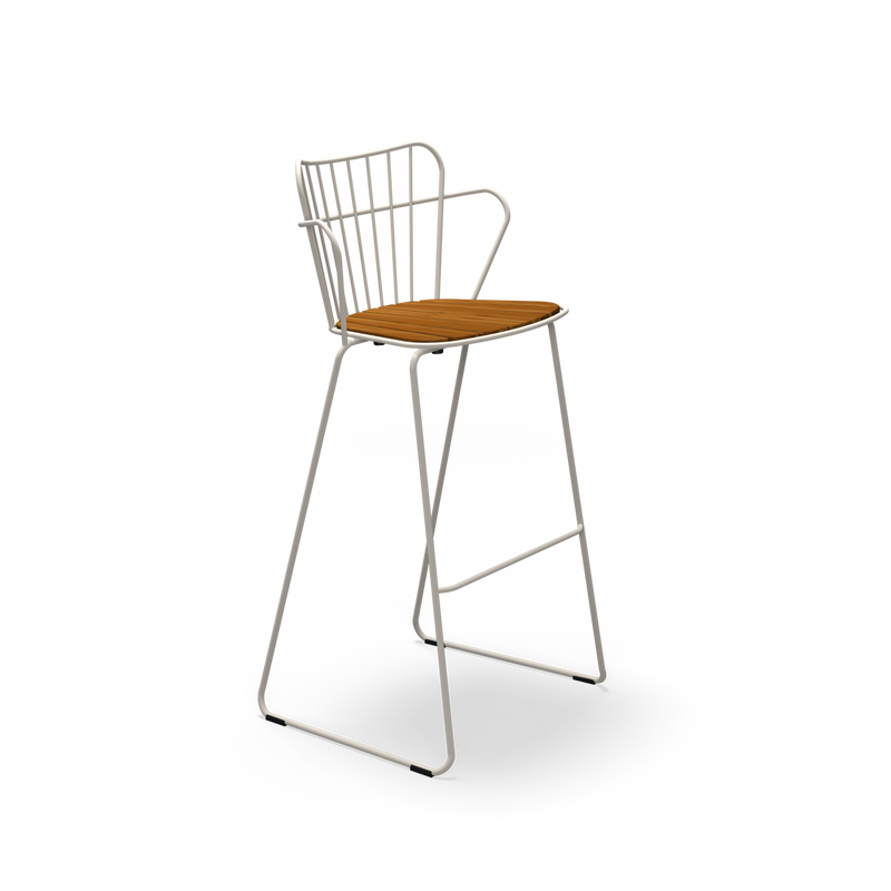 The Paon Barstool by Houe features a stylish minimalist design with a metal frame and wooden seat. It boasts a high back with vertical bars, angled legs with a footrest, and its Scandinavian-inspired aesthetic blends beautifully with the black frame and natural-finish seat.