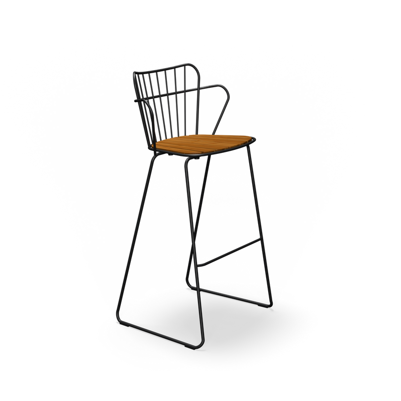 The Paon Barstool by Houe features a tall, modern design with a slender black metal frame and wooden seat, embodying Scandinavian style. Its backrest with a minimalist wire motif echoes PAON chairs, seamlessly integrating with the footrests.