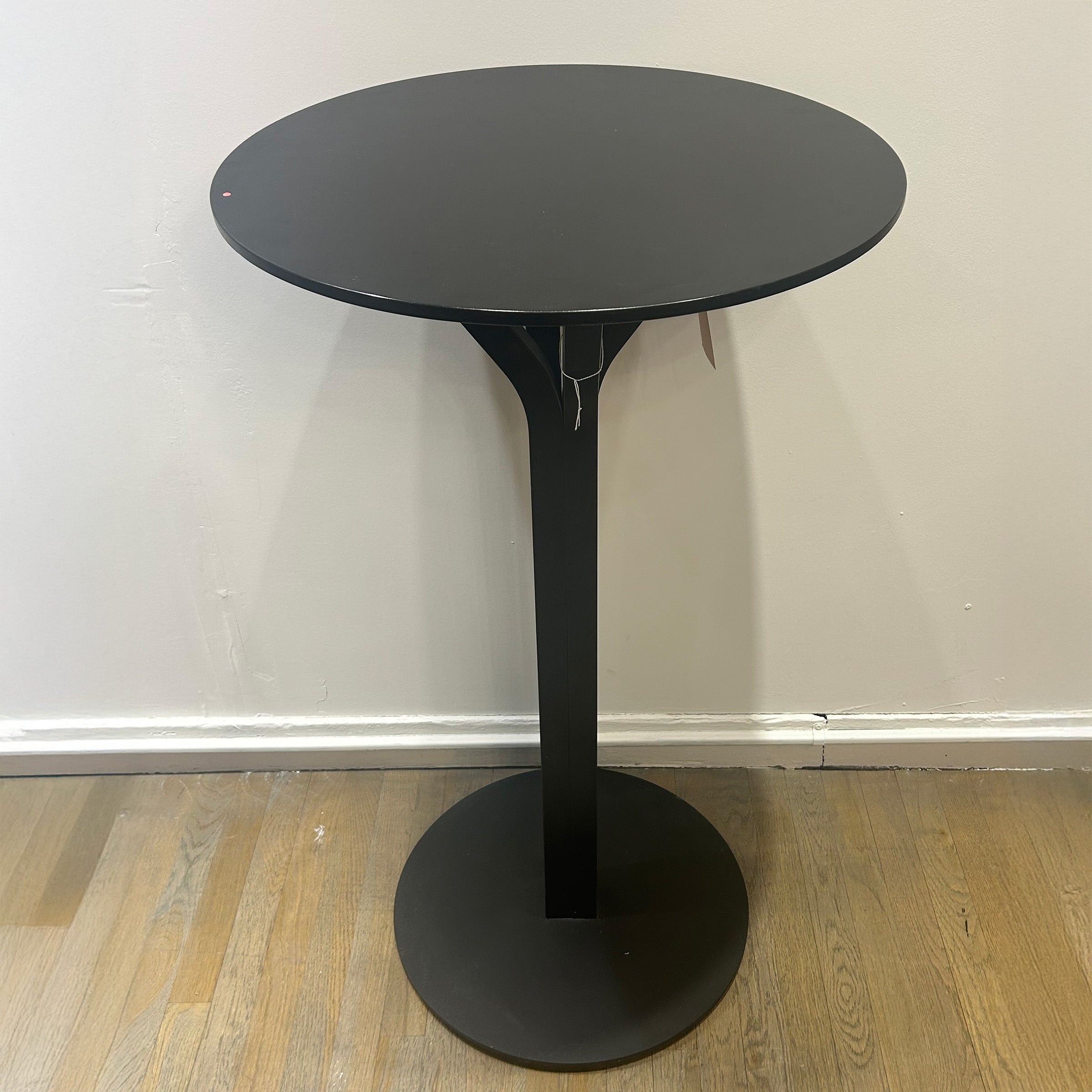 Bloom Bar Table Round - Sale black round top with sleek pedestal base on wooden floor against white wall