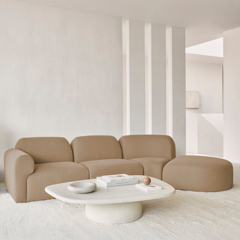 Beige sectional sofa in a minimalistic living room with a white coffee table.