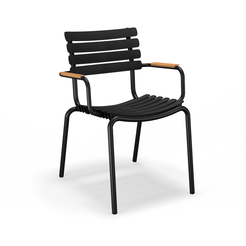 The ReClips Dining Chair with Bamboo Armrest by Houe features a black modern design with slatted plastic lamellas for the seat and back. It includes curved metal armrests accented with natural wood, four straight legs, and embodies true Danish design, blending sleek aesthetics with functional elegance.