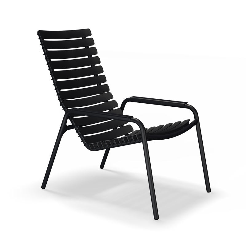 The ReClips Lounge Chair by Houe is a modern, black, slatted piece with a sleek metal frame and angled backrest. Highlighting elegant Danish design, its crafted from recycled plastic for sustainable sophistication and photographed against a plain black backdrop.