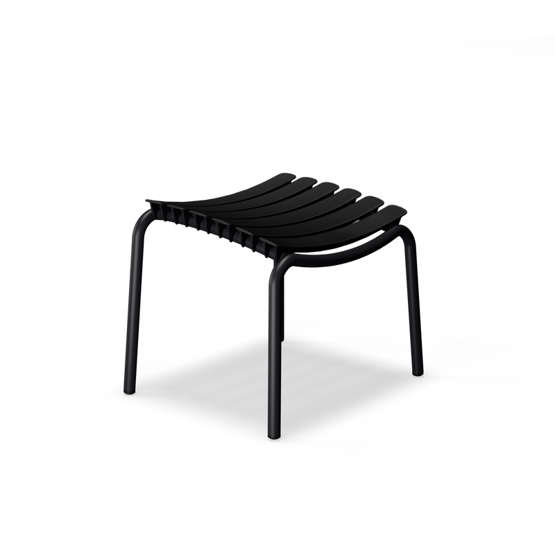 The ReClips Footrest by Houe features a sleek Danish design with a black seat made from recycled plastic and curved slats, supported by four tubular legs. Its weather-resistant qualities make it perfect for versatile use against a dark, minimalist background.