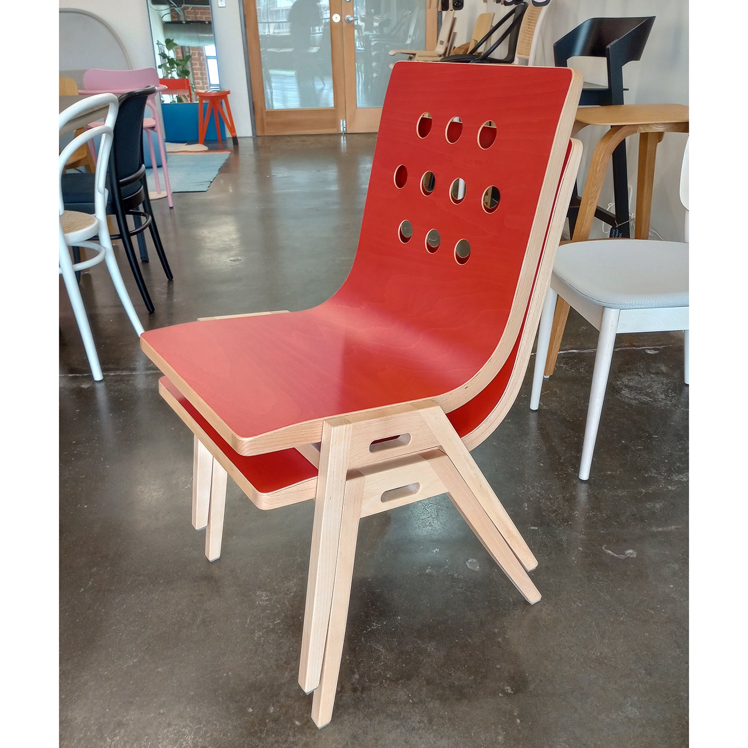 3/4/3 Side Chair with red plywood seat, beech wood frame, and circular hole pattern design in modern stackable style