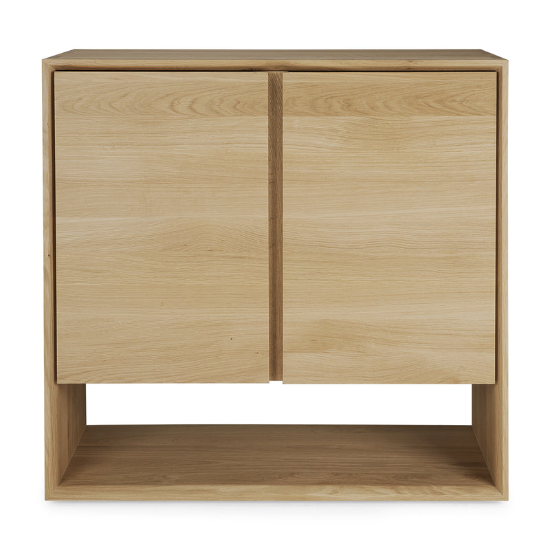 The Ethnicraft Nordic Sideboard is a modern, minimalist cabinet with two doors, a natural light wood finish, beveled edges, clean lines, and an open shelf at the bottom.