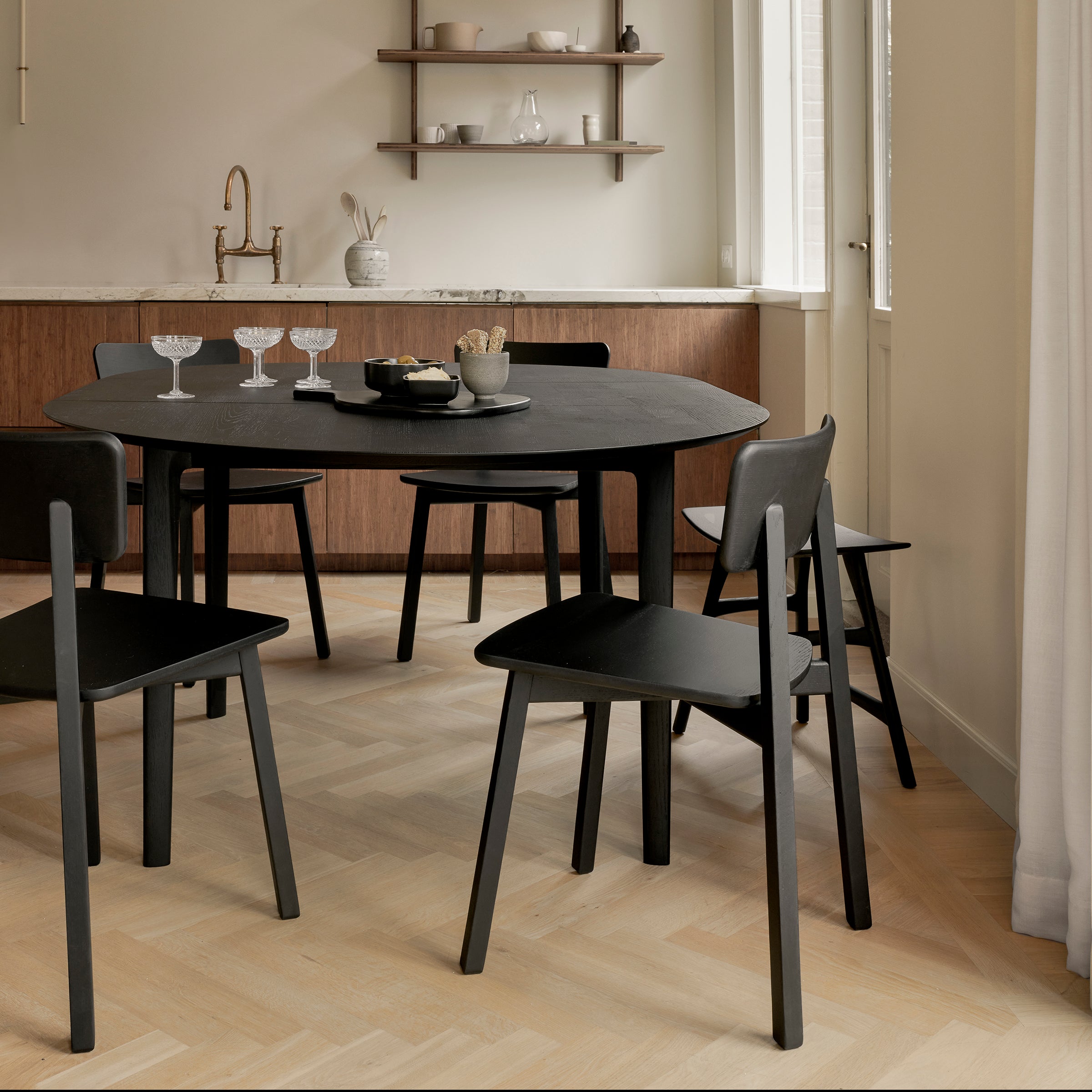 Bok Extendable Dining Table - Round in solid black oak with matching chairs in a modern dining room setting.