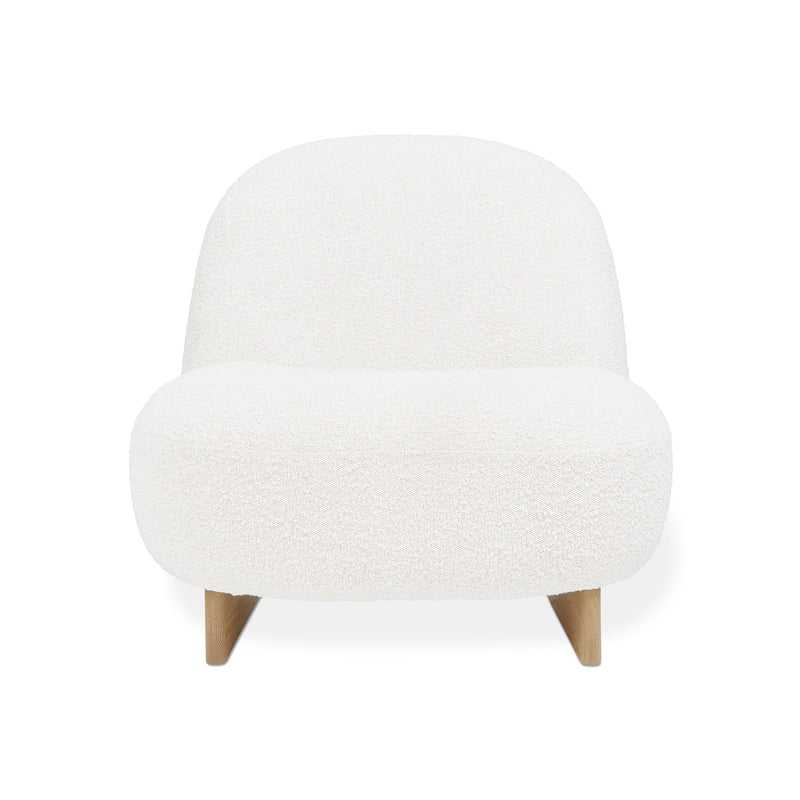 The Arlo Chair by Gus Modern showcases Scandinavian style with a rounded, armless lounge design, upholstered in white bouclé and supported by short, angled wooden legs.