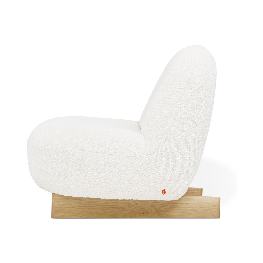 Side view of the Arlo Chair by Gus Modern, showcasing a white bouclé fabric seat and backrest on a low, light wood base. This minimalist lounge chair highlights contemporary Scandinavian-inspired design with a textured look.