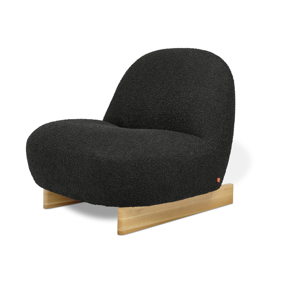The Gus Modern Arlo Chair features Scandinavian-inspired design with a rounded plush black bouclé seat and backrest, set on a simple light wood base against a white background.