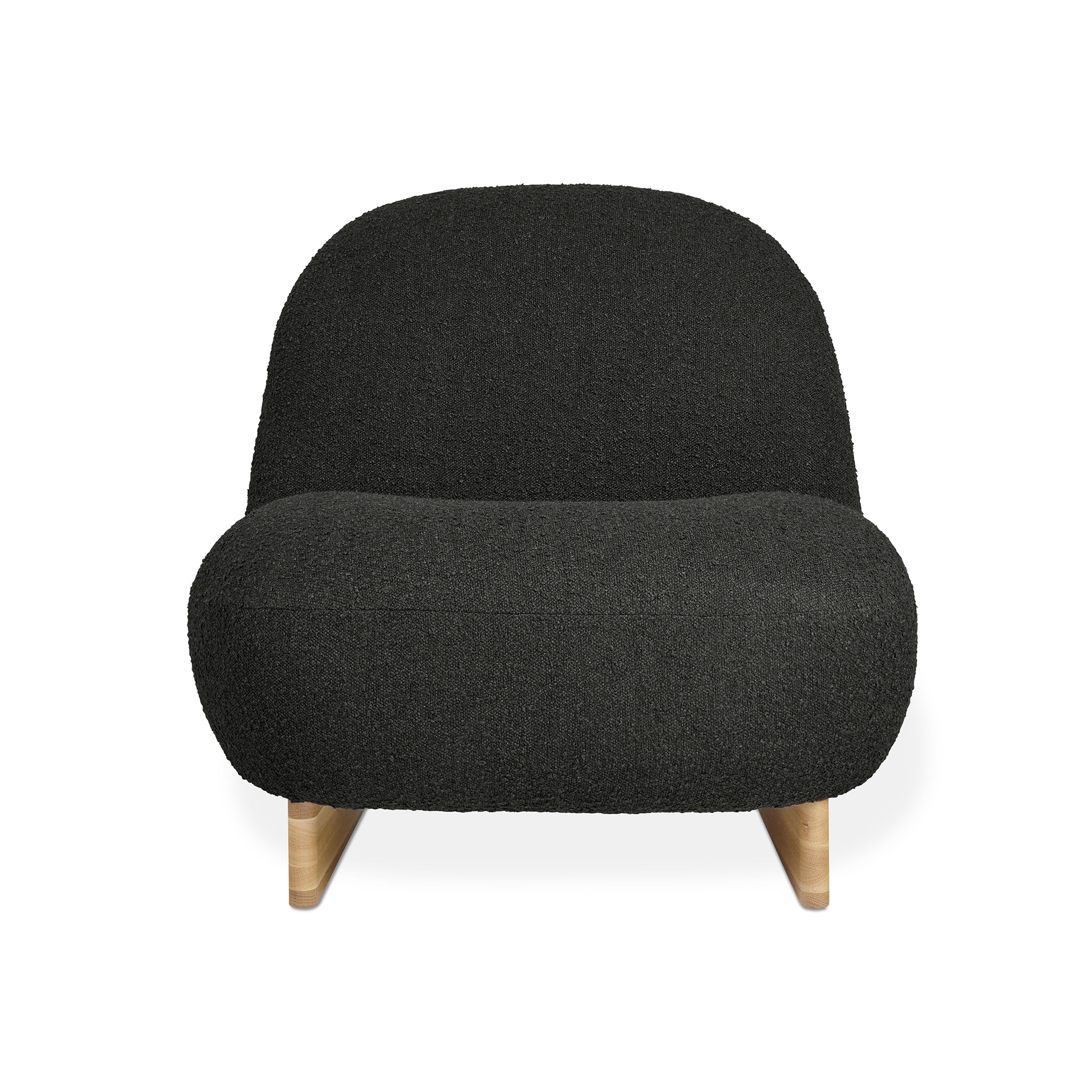 The Arlo Chair by Gus Modern features a modern, low-profile design with a rounded back and seat in black bouclé upholstery, set on light wooden legs that highlight classic Scandinavian style.