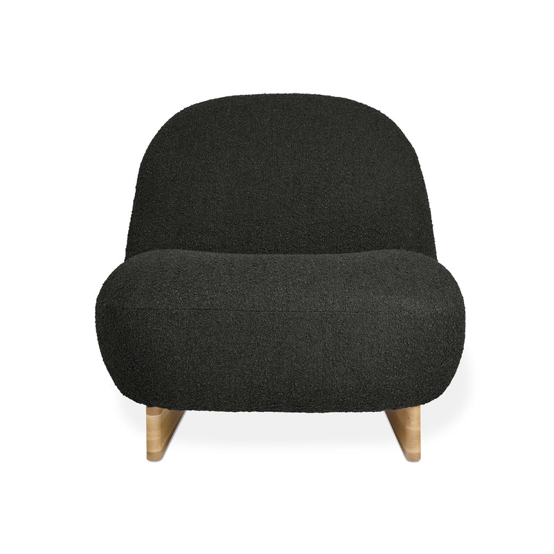 The Arlo Chair by Gus Modern features a modern, low-profile design with a rounded back and seat in black bouclé upholstery, set on light wooden legs that highlight classic Scandinavian style.