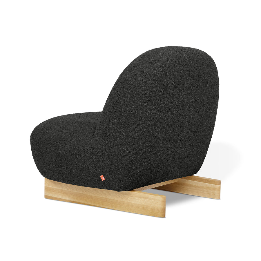 The Arlo Chair by Gus Modern features a curved black bouclé seat and backrest on light wooden sled-style legs, shown from the back and side against a white background.