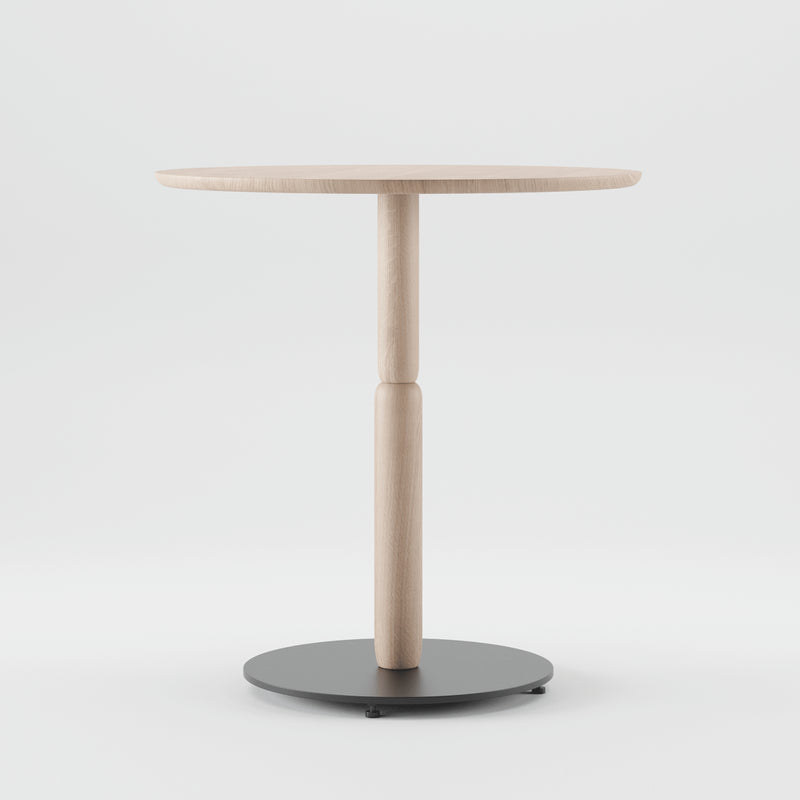 The Bistro A Table by Artisan is a minimalist, round table with a slender central support on a circular black base, crafted from solid wood. Set against a plain white background, it uses eco-friendly materials, prioritizing renewable resources without compromising style.