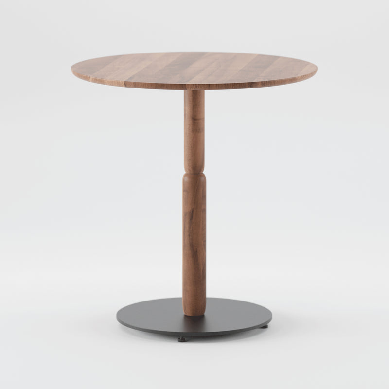 The Artisan Bistro A Table is a round wooden table made from solid wood with a smooth finish, featuring a single central wooden pedestal and a circular black metal base, showcased against a plain white backdrop.