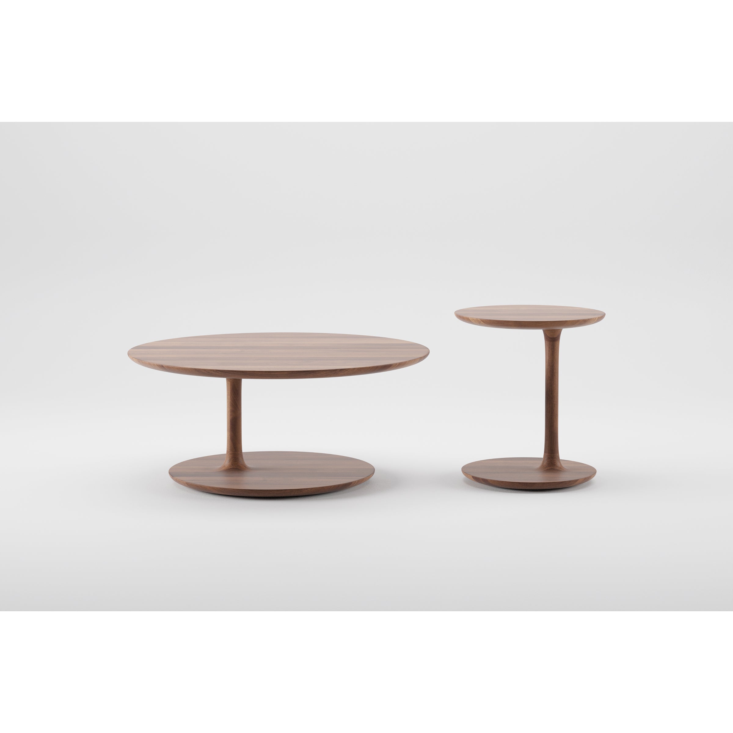 Against a plain background, two BLOOP Coffee Tables by Artisan are displayed: the larger low table on the left with a wider diameter and its taller, thinner companion on the right. Both tables showcase precision craftsmanship using 5-axis technology.