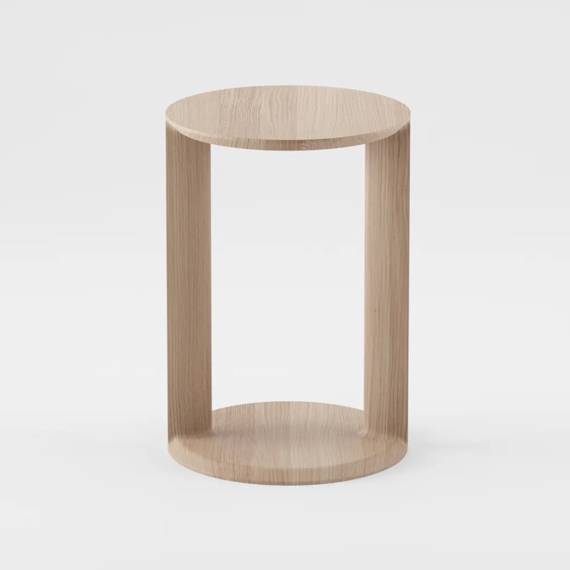 The BOAZ Sidetable by Artisan is a minimalist wooden side table crafted from solid wood featuring a circular top and base connected by three vertical panels. Its light wood, enhanced with natural oils, has a smooth finish that provides a sleek and modern look against a plain white background.