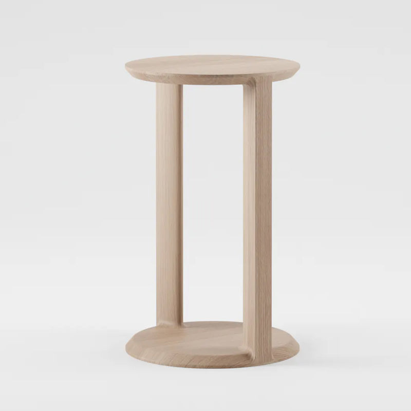 The BOAZ Sidetable by Artisan is a round wooden stool crafted from solid wood and finished with natural oils. Featuring a circular top and base connected by three vertical supports, the simple design stands out against a plain white background, highlighting its minimalist and eco-friendly appeal.