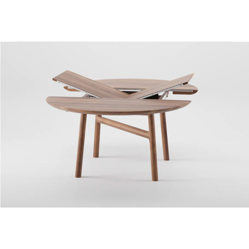 The DASH Extendable Table by Artisan features a unique expanding mechanism with a round solid wood tabletop, partially open with overlapping segments finished in natural oils. Its four wooden legs add a modern, eco-friendly touch.