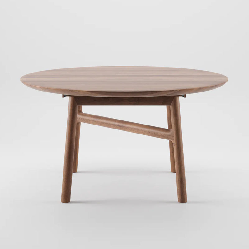 The DASH Extendable Table by Artisan is a round table crafted from solid wood, featuring a smooth surface and angled legs connected by a support. Finished with natural oils for an eco-friendly appeal, its minimalist design stands out against a plain white background.