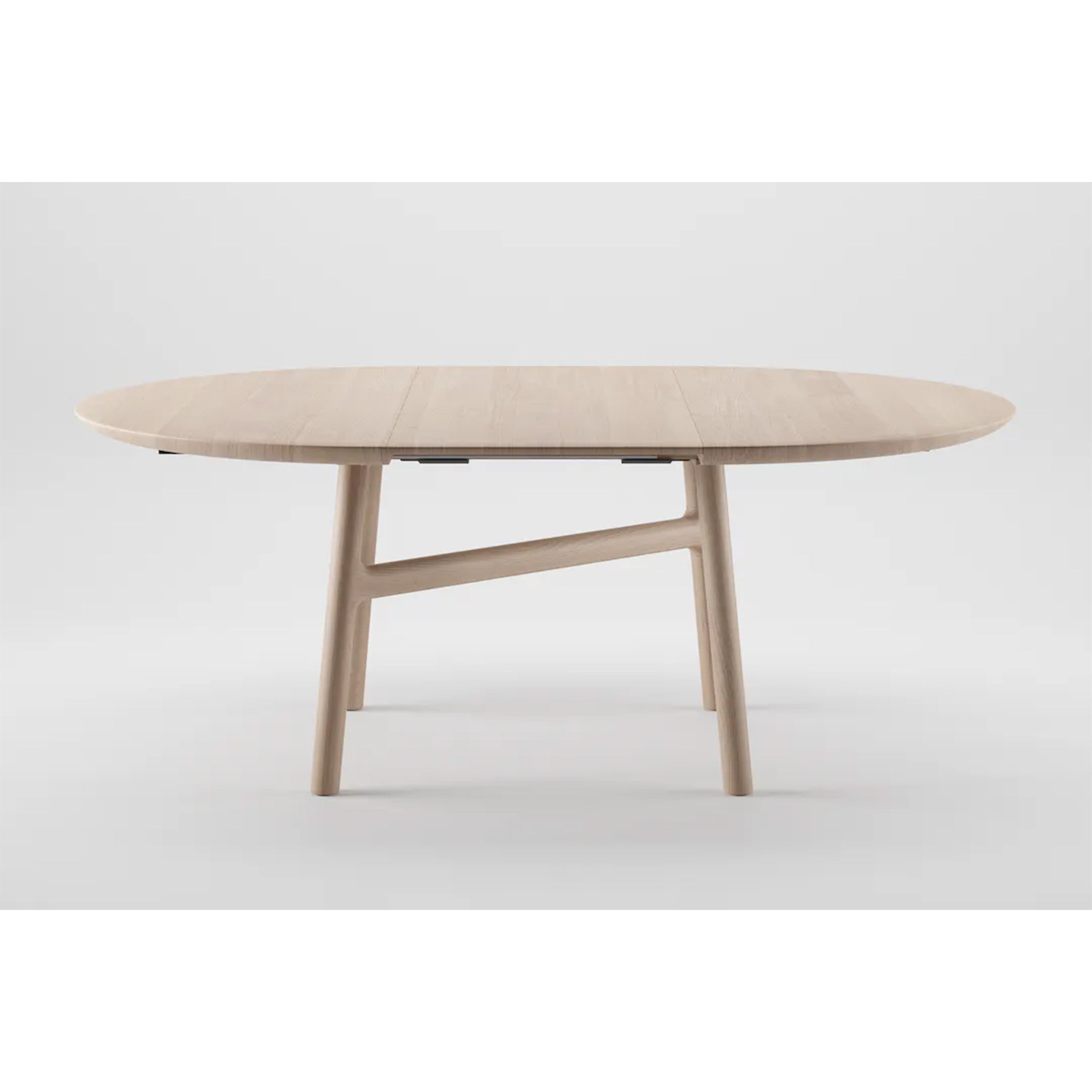 The DASH Extendable Table by Artisan is an environmentally-friendly, wooden oval table with a light finish. Its crafted from solid wood, enhanced with natural oils, and features a distinctively angled central support and clean lines in a minimalist design.