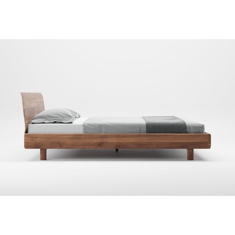 The FIN Bed by Artisan features a minimalist design with a solid wood frame and headboard. Photographed against a plain white backdrop, it is adorned with a gray pillow and neatly folded gray blanket, highlighting its organic beauty and simple elegance.