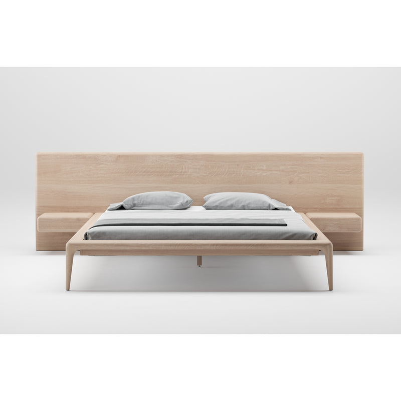 The Artisan LATUS Bed is a minimalist design crafted from solid wood, featuring a large headboard and integrated side tables. It includes gray and white bedding, boasts an eco-friendly natural finish, and stands out against a plain white background.