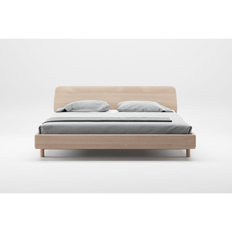 The Artisan FIN Bed features a minimalist, eco-friendly wooden frame and headboard with natural textures. Its simple, modern design is complemented by a gray bedspread and two light gray pillows against a plain white background.