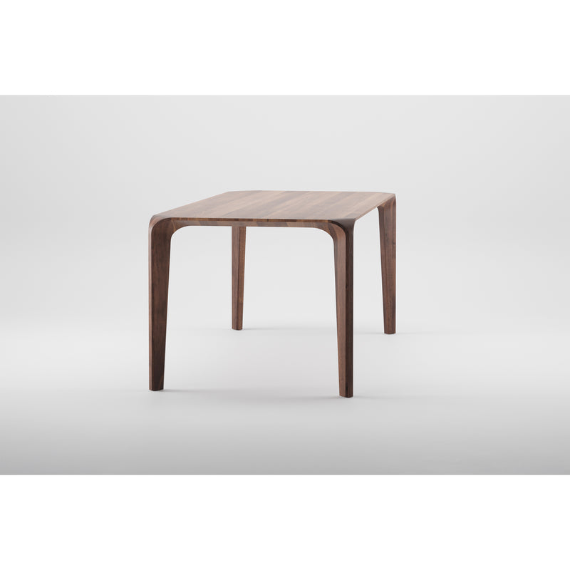 The FLOW Table by Artisan is a minimalist piece crafted from solid wood, featuring a rectangular top and slender curved legs. Set against a white background, its finished with natural oils for a smooth touch and an eco-friendly, modern design.