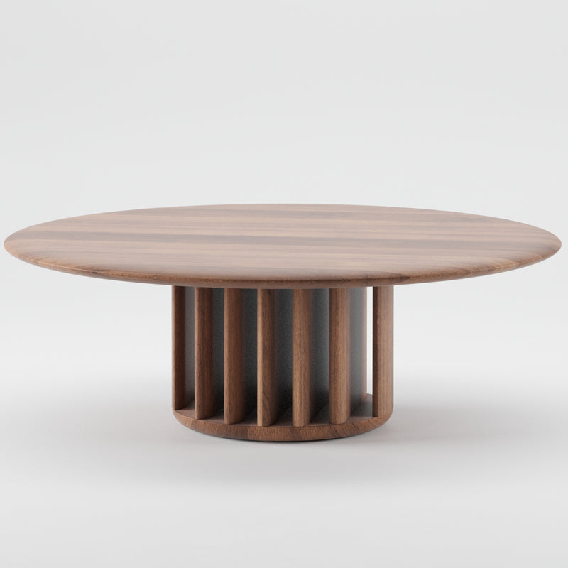 The Artisan GRID Coffee Table features a round, smooth, flat wooden top and a unique cylindrical base of vertical slats. Made from sustainable materials, its modern design beautifully combines functionality with aesthetic artisan appeal, highlighted against a plain white background.