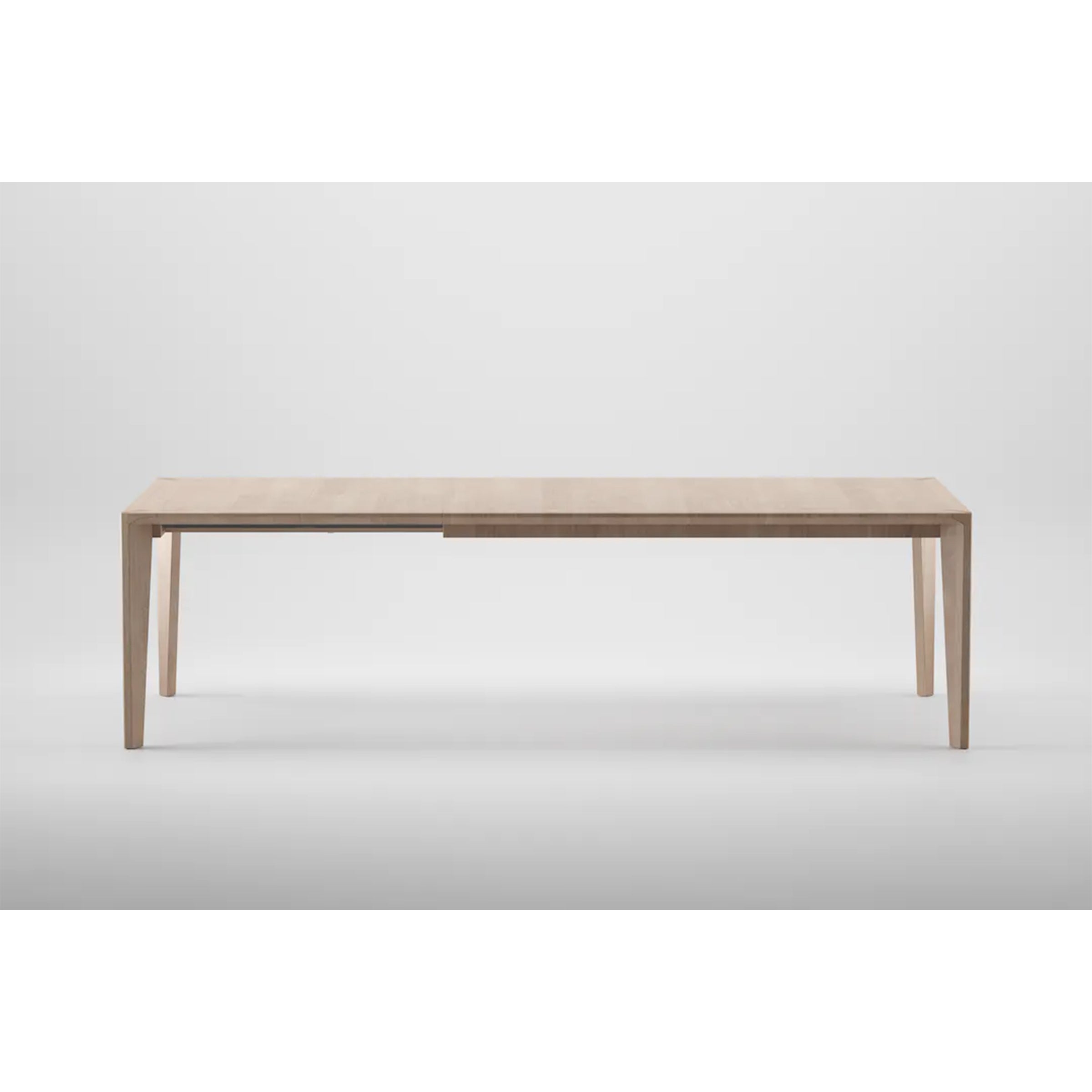 The HANNY Extension Table by Artisan is a minimalist wooden dining table crafted from solid wood with a natural texture. It features a rectangular top, sleek tapered legs, and environmentally-friendly materials set against a gray background.